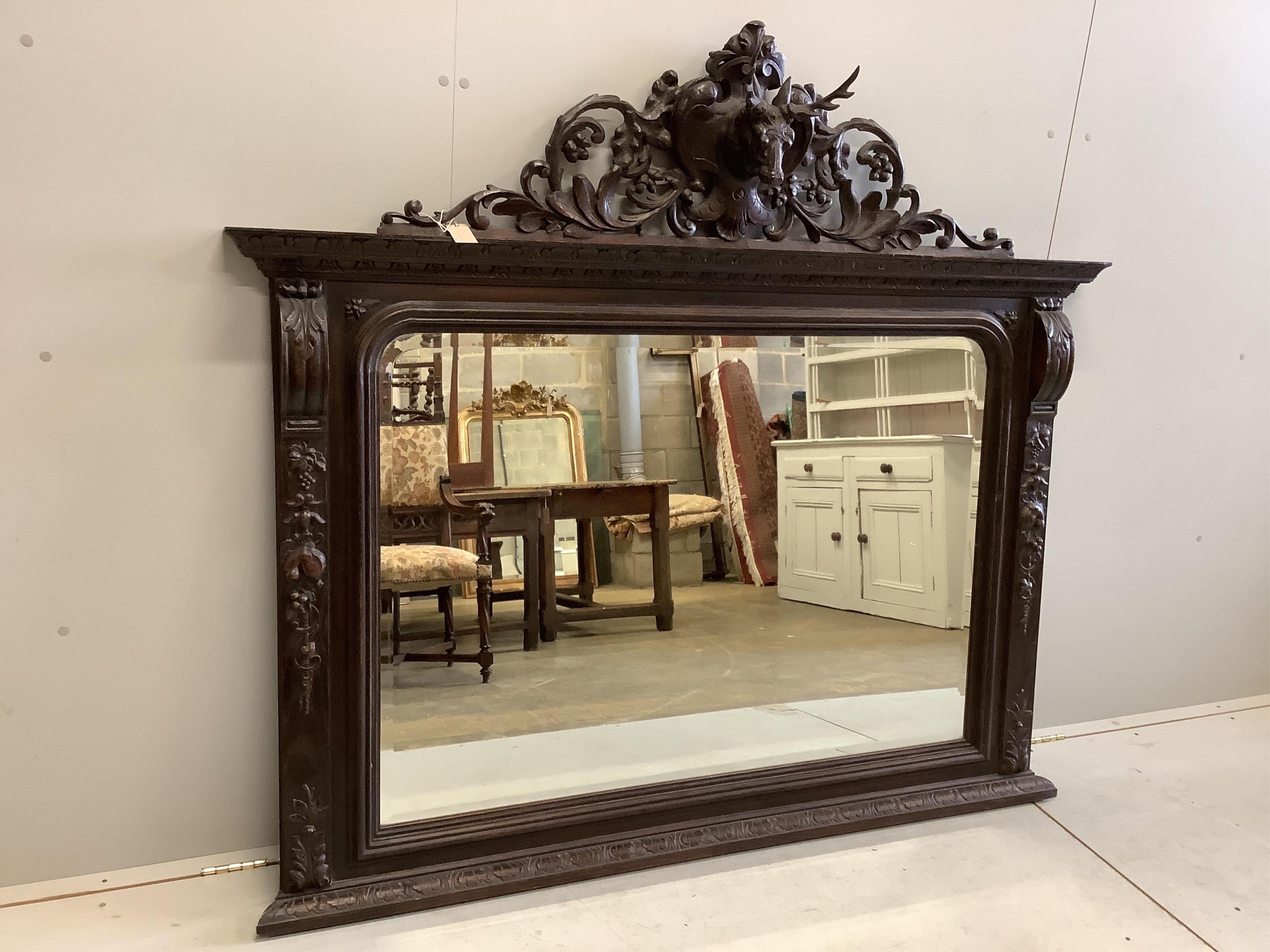A Victorian oak overmantel mirror with carved stag's head pediment, width 163cm, height 146cm. Condition - fair